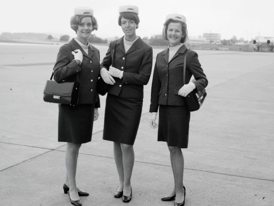 Schwarzweissfoto: Drei Frauen in Uniform mit knielangen Röcken und weissem Filzhut
