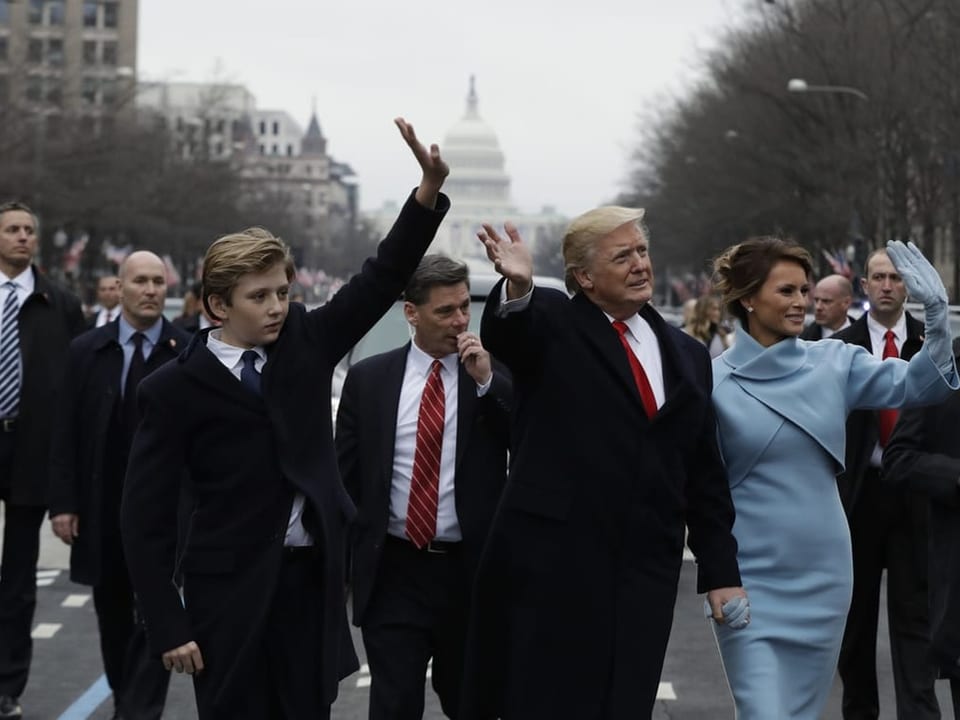 Trump läuft winkend gemeinsam mit seiner Frau Melania Trump und ihrem Sohn Barron auf der Parade.