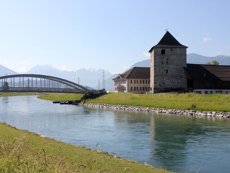 Schloss Grynau am Wasser. Über den Fluss führt eine Brücke.