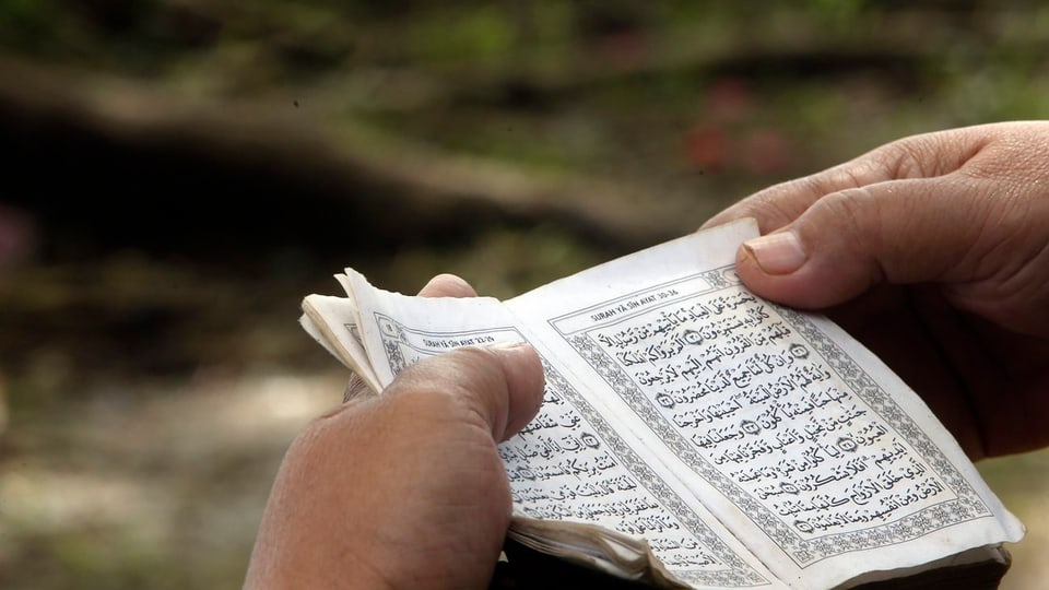 Zwei Hände halten einen Koran.