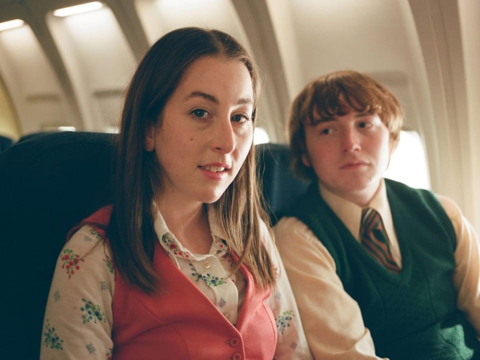 Eine junge Frau und ein junger Mann sitzen im Flugzeug.