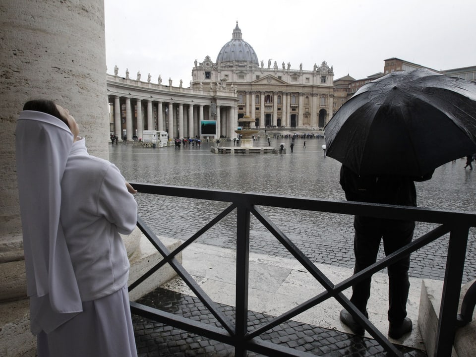 Nonne betet gen Himmel auf dem regnerischen Petersplatz.