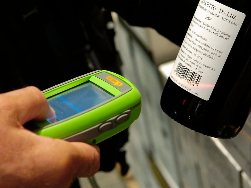 Hand eines Kunden mit Scanner und Weinflasche.
