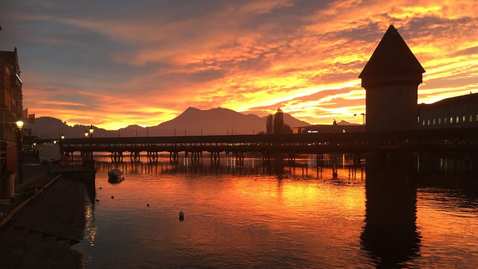 Kapellbrücke in Luzern mit Pilatus und einem goldenen Morgenhimmel.