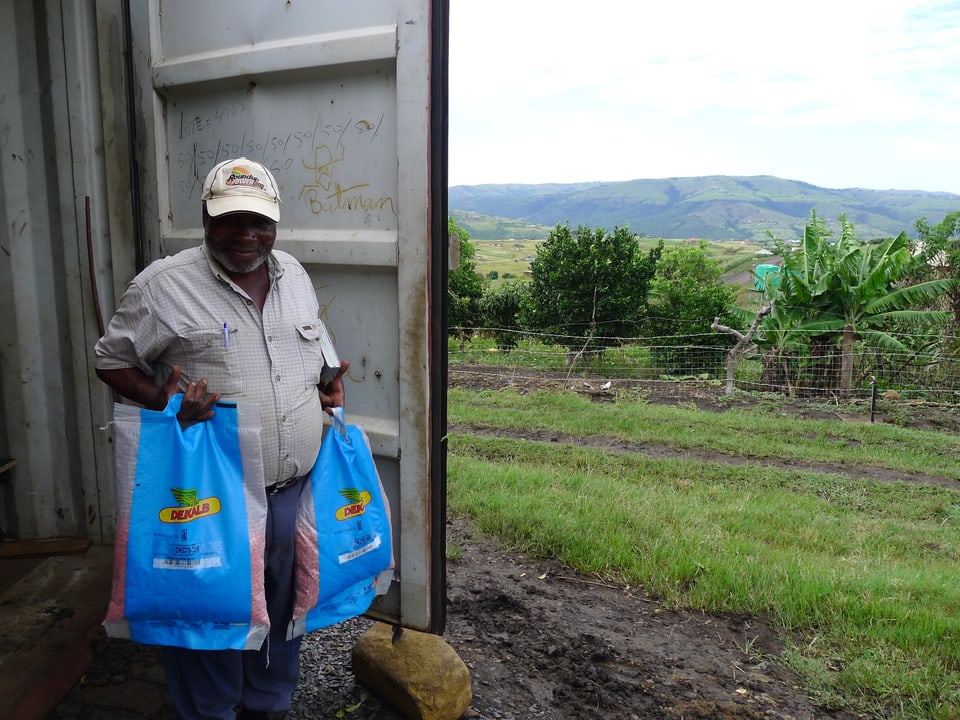 Der 72-jährige Kleinbauer Muzizegonia Ngema mit zwei Säcken mit Saatgut, mit dem er Gentech-Mais anbaut.