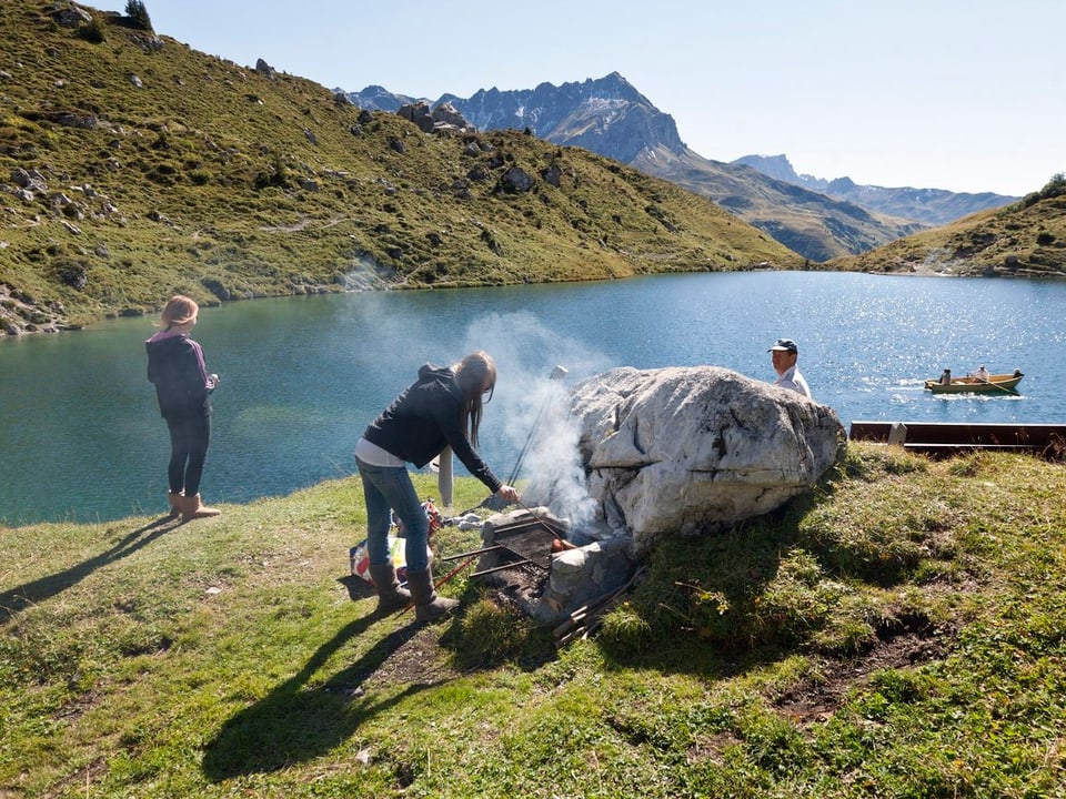 Berg- und See-Romantik: Eine Gruppe grilliert im Sommer an einem Bergsee.