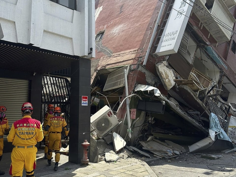 Such- und Rettungsteams laufen auf ein eingestürztes Gebäude zu.