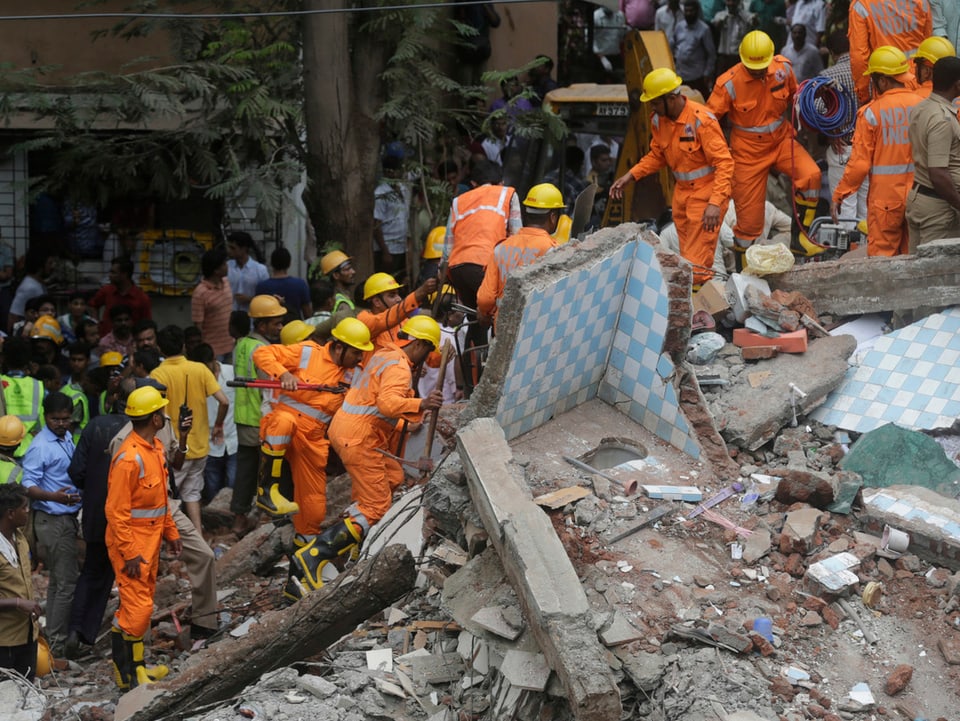 Rettungskräfte suchen in Trümmern nach Überlebenden.