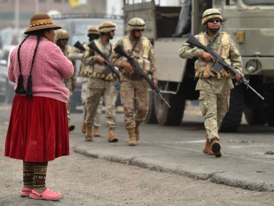 Eine Frau in Arequipa beobachtet eine Militär-Patrouille.