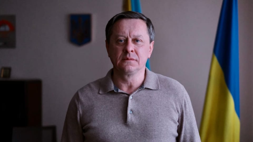 Oleksandr Hontscharenko steht neben einer ukrainischen Flagge und schaut direkt in die Kamera.