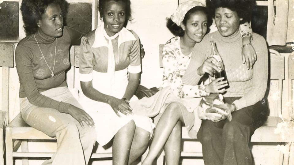 Vier junge schwarze Frauen auf einer Bank.