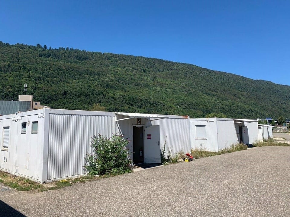 Weisse Stahlcontainer, kleine Fenster, Zäune
