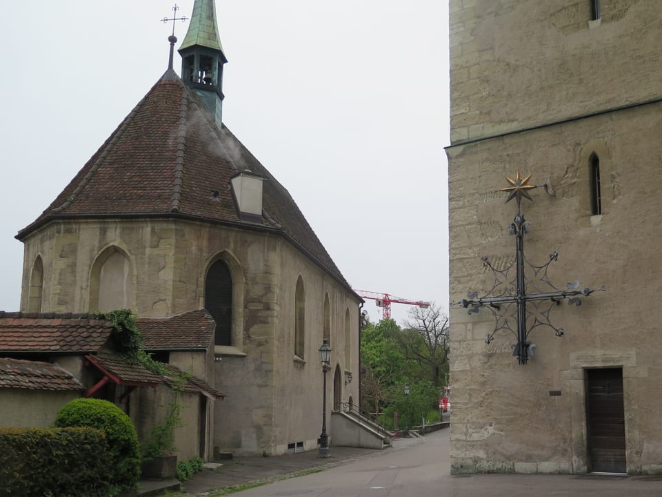Eine kleine Kirche, daneben ein grösseres Gebäude.