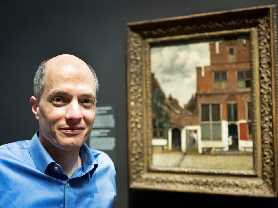 Alain de Botton vor einem Bild im Reichsmuseum.