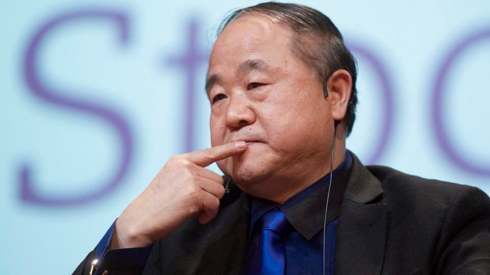 Der chinesische Schriftsteller Mo Yan hält in nachdenklicher Pose den Finger an seinen Mund.