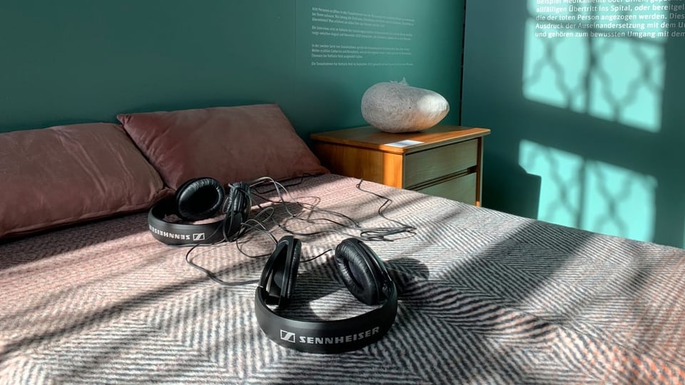 Bett mit Kopfhörern in der Ausstellung