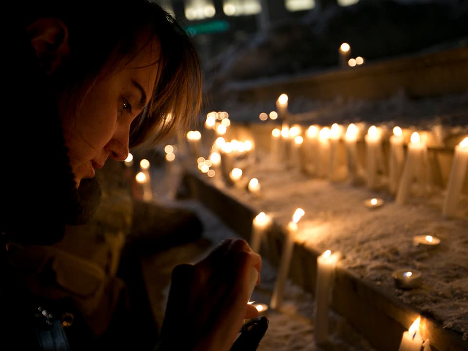 Eine junge Kosovarin entzündet eine Kerze.