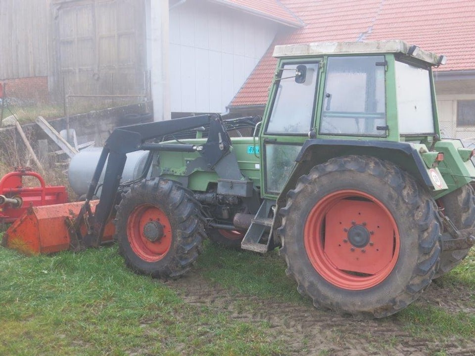 Ein Traktor neben einem Schopf.