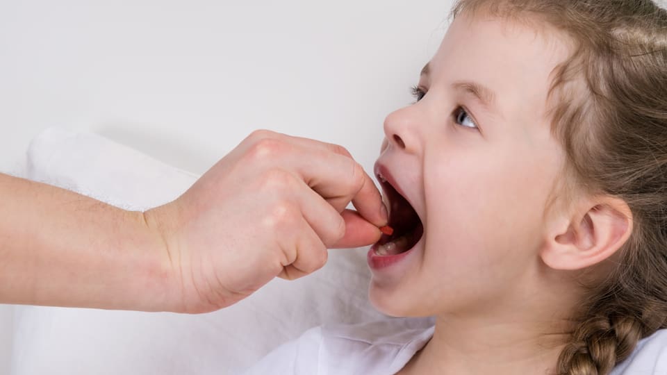 Eine Erwachsener führt einem Mädchen eine Polle zum Mund. (colourbox)