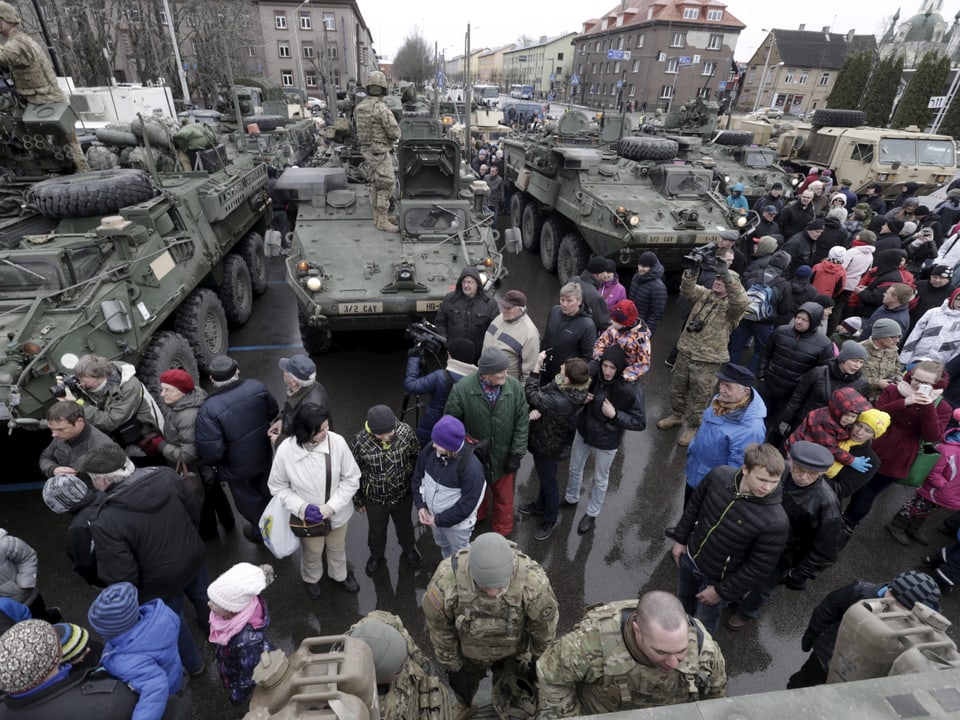 Menschen stehen um mehrere Panzer herum