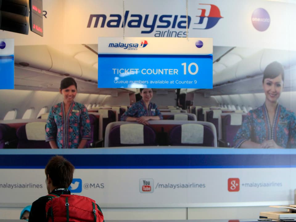 Mann am Ticketschalter von Malaysia Airlines in Kuala Lumpur