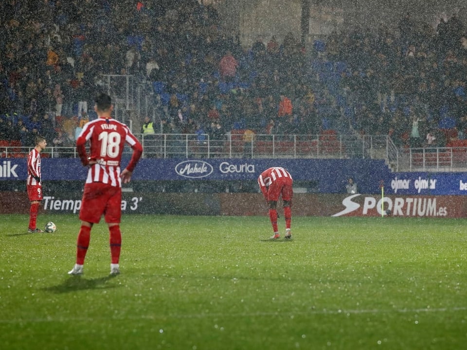 Atletico-Spieler stehen im Regen.