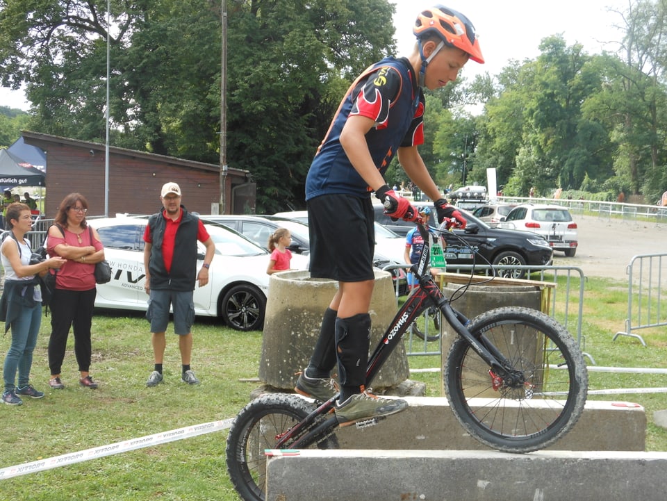 Ein Jugendlichen balanciert mit seinem Mountainbike auf einer Steinmauer. 