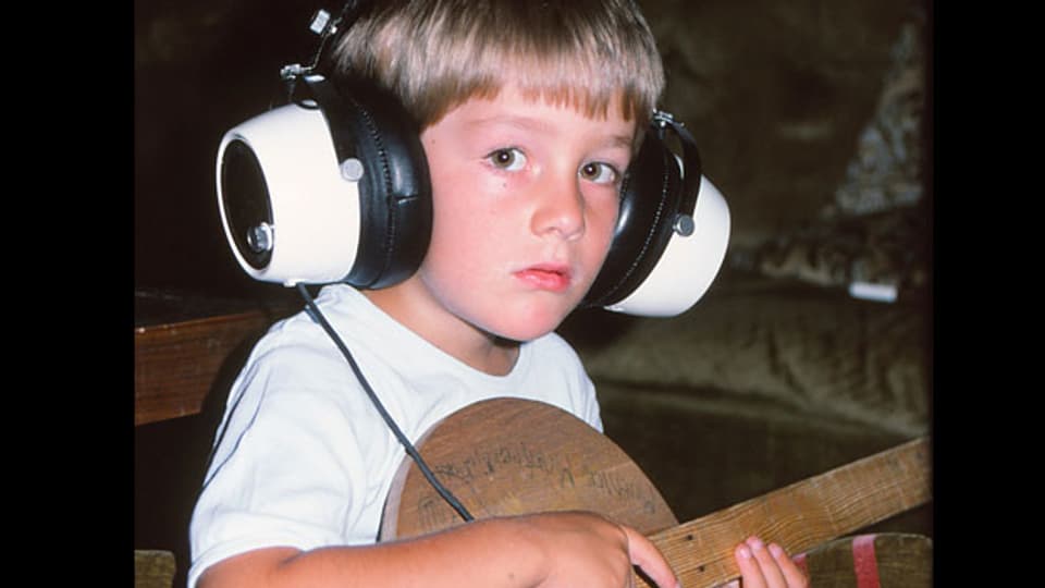 Michael Brunner mit Kopfhörern und Gitarre.