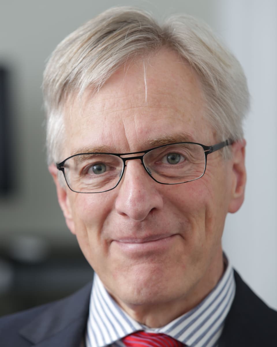 Professor Ulrich Schnyder, Direktor der Klinik, mit weissen, kurzen Haaren, schwarzer Brille mit dünnem Rand und einem Lächeln.