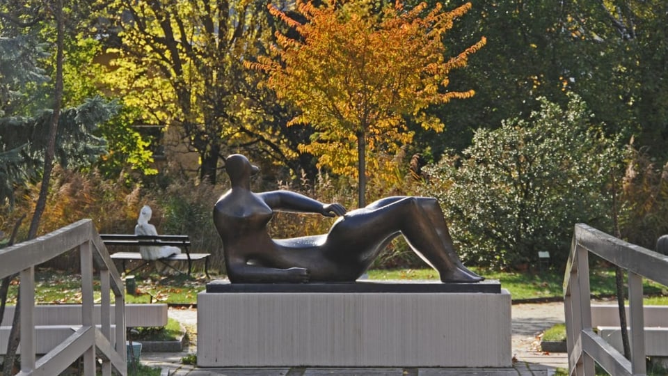 Bronze-Skulptur einer liegenden Person in einer Parkanlafe