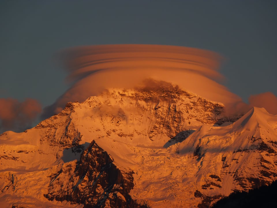 Eine Wolke hüllt den Gipfel der Jungfrau ein. Der starke Wind zeichnet Bänder in die Wolke, sie sieht nun einem Ufo ähnlich.