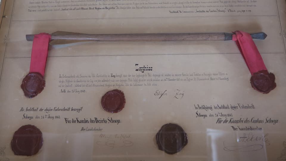Ein Pfeil in einem Rahmen hinter Glas mit einer Urkunde und Siegeln aus dem Jahr 1862.