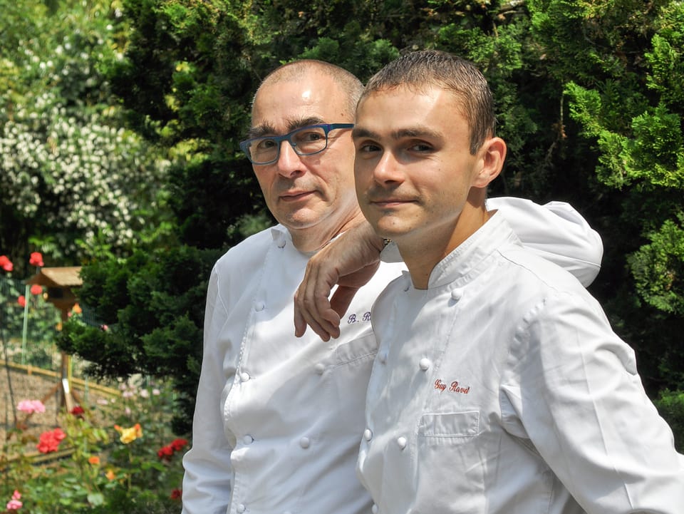 Bernard und Guy Ravet posieren in Kochuniform im Garten.