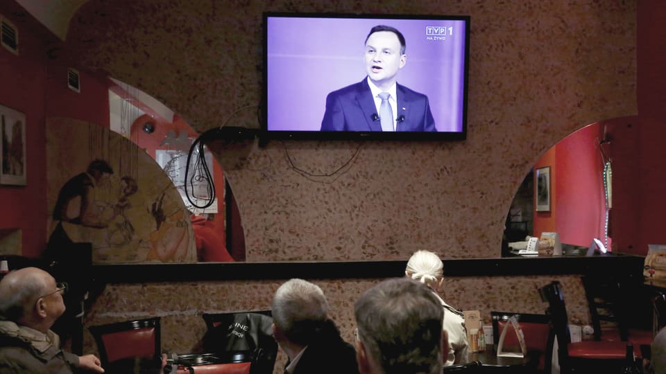 Polnische Männer sitzen vor einem Bildschirm, darauf zu sehen: Andrzej Duda von «Recht und Gerechtigkeit» beim TV-Duell vor den Wahlen 2015.