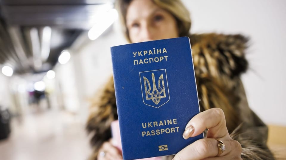 Eine Frau hält einen ukrainischen Pass in die Kamera des Fotografen