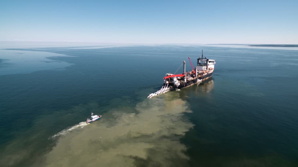 Ein Schiff zieht ein Rohr der Pipeline Balticconnector ins Meer.