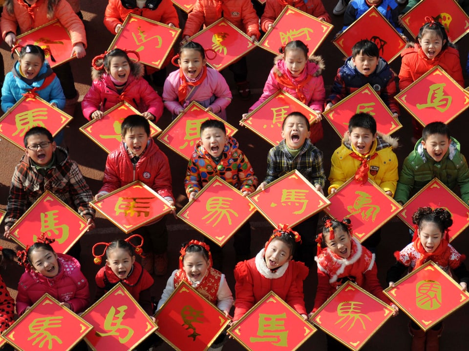 Kinder zeigen ihre Scherenschnitte zum chinesischen Jahr des Pferdes.