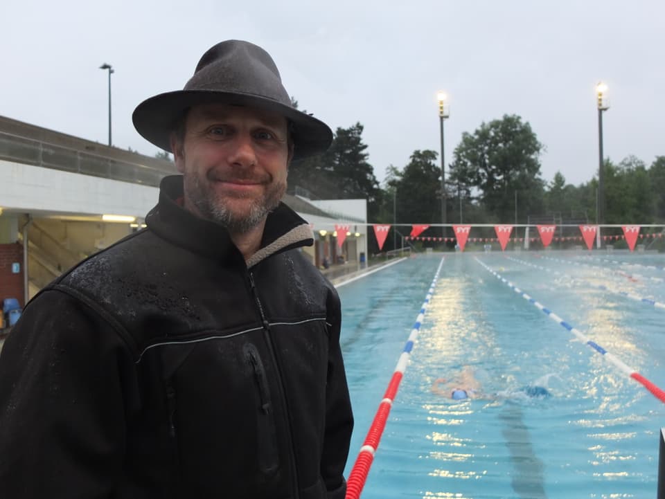 Mann mit Hut steht vor dem Schwimmbecken