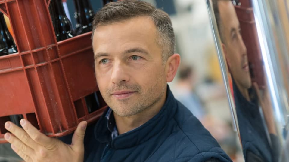 Gascho Mann trägt eine Kiste Bier.