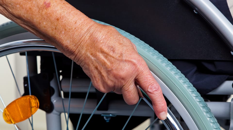 Nahaufnahme Hand an einem Rollstuhl-Rad.