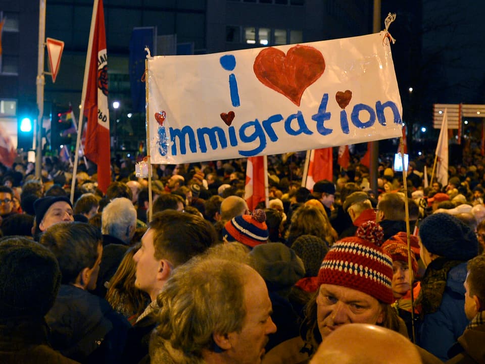 Hunderte von Leuten auf der Strasse, dazwischen ein Transparent mit der Aufschrift «I love immigration»