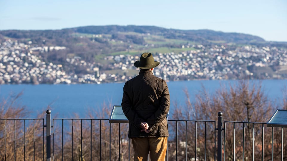 Älterer Mann mit Hut blickt auf den Zürichsee. 