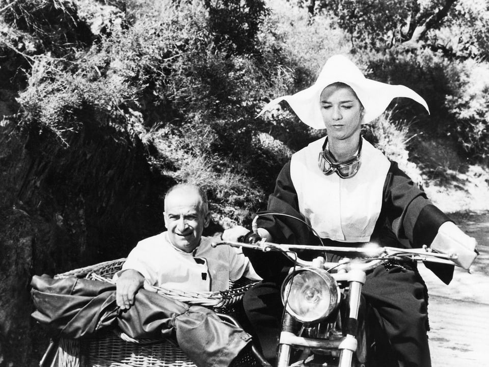 De Funès als Beifahrer auf dem Motorrad, das von einer Frau gefahren wird.