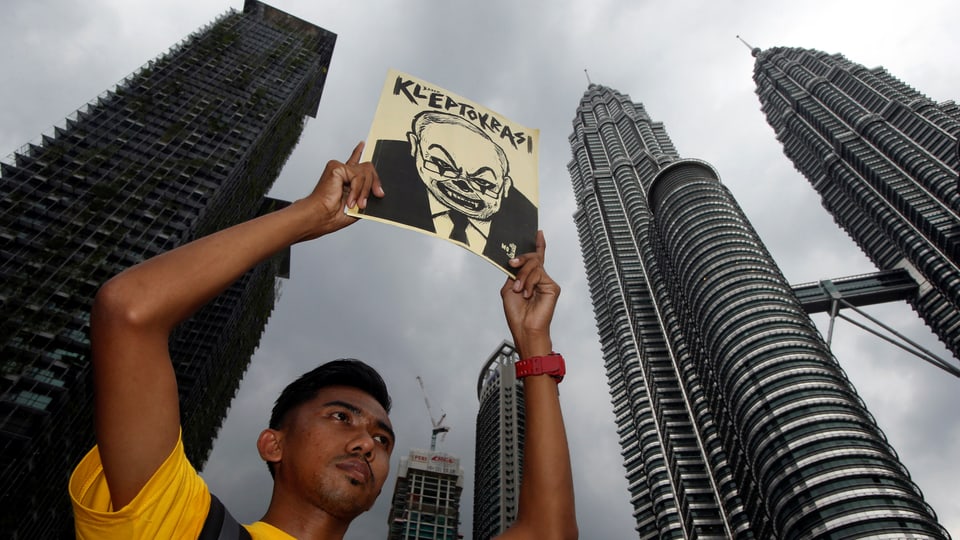 Ein Demonstrant hält einen Flyer hoch mit einer Karikatur von Najib mit der Überschrift «Kleptokratie».