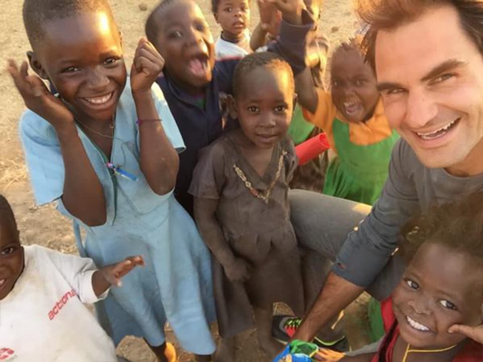 Roger Federer auf einem Bild mit sieben strahlenden maawischen Kindern