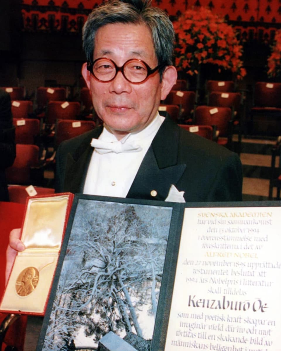 Ein Mann mit Brille und der Nobelpreis-Urkunde in der Hand.