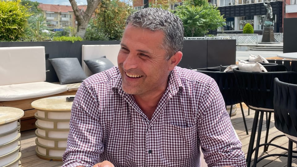 Smiling man with checked shirt in outdoor cafe.