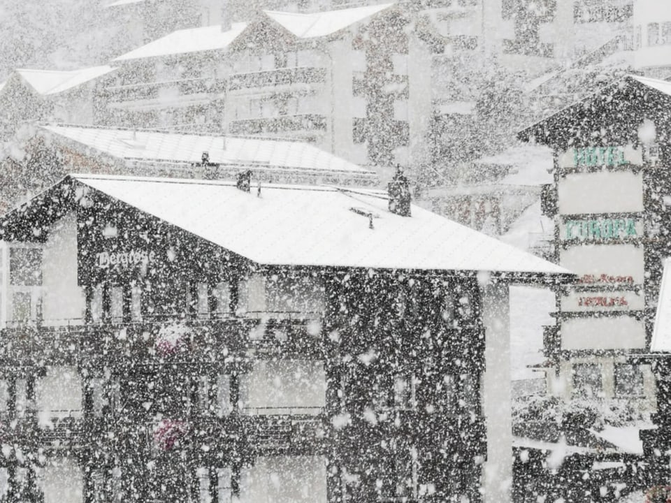 Starker Schneefall vor Häusern.