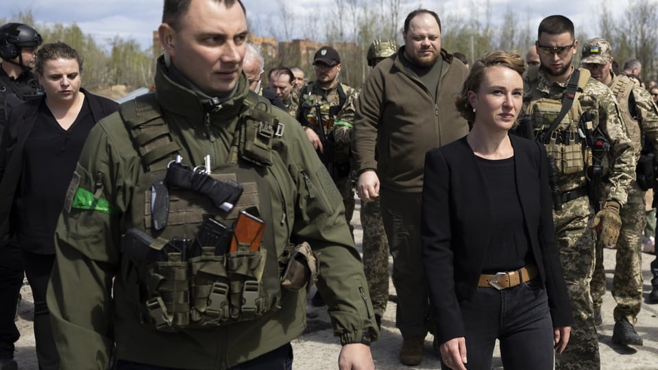 Frau in Schwarz, umgeben von Männern in Militärausrüstung