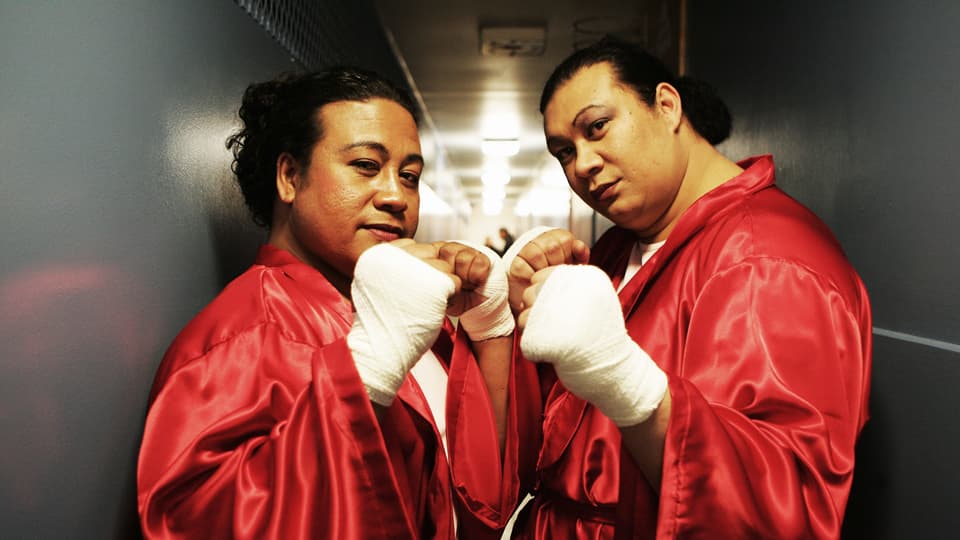 Zwei geschminkte samoanische Boxer in rotem Satinboxmantel posieren in Boxhaltung.